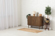 © Pixel-Shot - Stylish chest of drawers with lamp, decor and plants near white brick wall in room
