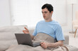 © New Africa - Sick man having online consultation with doctor via laptop at home