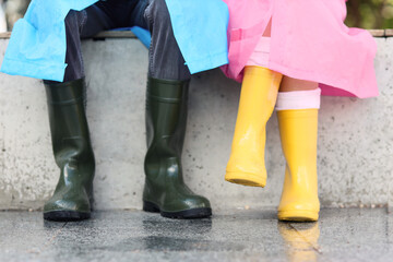 Couple wearing raincoats and gumboots on rainy day outdoors