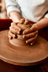 Hands, pottery wheel and woman with clay, productivity and creativity in workshop, hobby and tools. Closeup, entrepreneur and person with equipment, designer and artist with process or small business