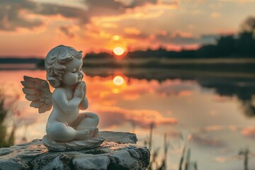 Little ceramic angel sits praying on a rock in the silent lake at sunset, background image for mourning and farewell, death of a person