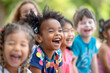 © sornram - Happy, diverse group of children laughing and enjoying outdoor play time, with lush greenery in the background.