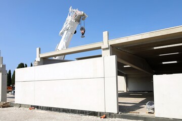 Wall Mural - White industrial building under construction. It is made of large prefab concrete panels. Mobile crane on background