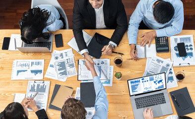 Wall Mural - Two businessman shake hand in meeting room with coworker give cheerful applause. Team of analyst celebrate after successful significant progress on business strategic performance. Meticulous