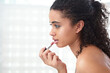 © Chanelle2000/peopleimages.com - Beauty, makeup and woman with lipstick in bathroom to get ready or prepare for date in home. Cosmetics, girl and apply product on lips for morning routine, skin and facial treatment for glow