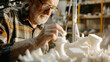 © VK Studio - An elderly man lost in concentration, meticulously crafting with white plastic pieces in a workshop, showcasing his dedication and skill.