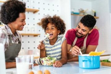 Wall Mural - Happy african american family preparing healthy food in kitchen, having fun together on weekend