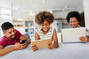 Wall Mural - Obsessed to tech devices happy african american family using digital tablet, computer, smartphones