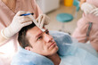 © dikushin - Close-up of unrecognizable female nurse drawing using pencil new hairline on head of handsome patient male before hair transplantation surgery in clinic. Concept of professional baldness treatment.