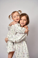 Wall Mural - A portrait of two sisters on a white background with copy space. Happy children having fun together.