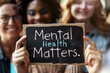 © Running opossum - Diverse group of people smiling while holding a sign promoting mental health awareness