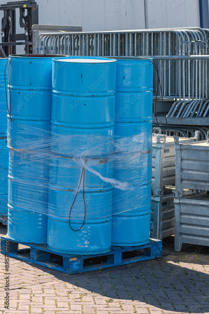 blue oil barrels are stacked outside on wooden industrial pallets