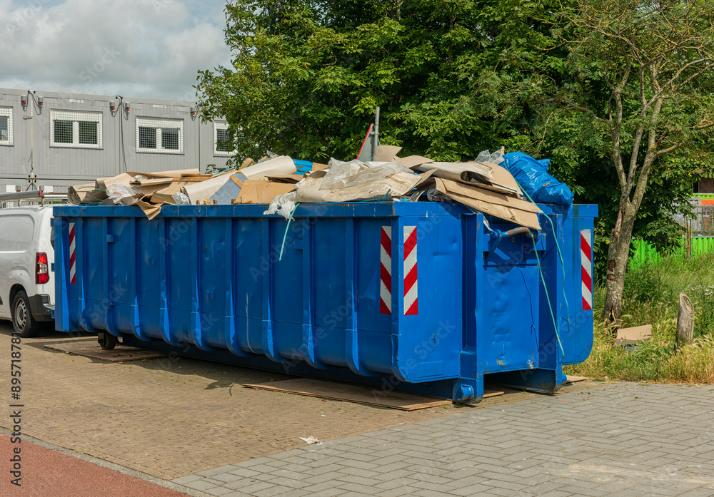 blue steel open industrial waste container filled with cardboard waste