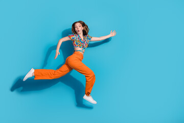 Wall Mural - Full size photo of nice young girl run jump empty space wear top isolated on blue color background