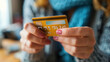 © khonkangrua - Close-up of a woman's hand holding a gold credit card, representing online shopping, finance, and digital transactions.