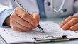 © Chatchanan - Doctor filling out a medical insurance claim form at a clinic, close-up of hands and form