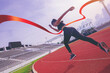 © Panumas - Fit young woman running sprinting to red finish line at the racetrack. Finisher, marathon runner sprinting moment at the racetrack.