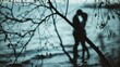 © pngking - Blurred silhouette of a young couple embracing in the sea Tree branches in silhouette in the foreground Monochrome toned seascape