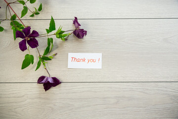 Poster - branch of blooming purple clematis, on a light wooden table