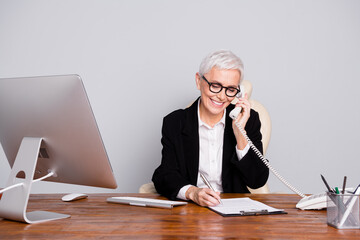 Canvas Print - Photo of pretty senior female professional entrepreneur sit table phone call wear formalwear specs isolated on gray color background