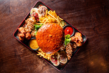 Poster - A colorful platter of fast food items including burgers, fries, and fried chicken on a dark wooden table