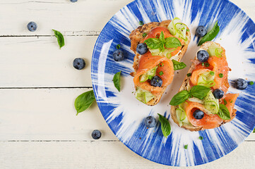 Wall Mural - Breakfast. Open sandwiches with salted salmon, cucumber and blueberry. Seafood. Healthy food. Top view, flat lay