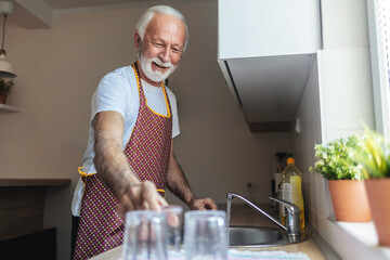 Cleaning, washing dishes or portrait of happy old man with soap water in kitchen sink in healthy home. Dirty, smile or senior male with liquid foam to disinfect, protect or prevent bacteria or germs