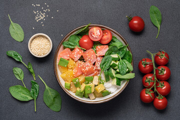 Wall Mural - Salmon bowl with spinach, rice, avocado, tomato, cucumbers on black background, top view. Poke bowl, healthy eating