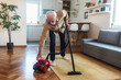 © Jelena Stanojkovic - Senior man using his vacuum cleaner. Bearded senior man vacuuming carpet, male cleaning house using vacuum keeping home clean, housekeeper, everyday life concept.