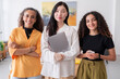© Studio Marmellata - Three confident women stand in a bright office space They are dressed in professional attire and pose confidently for the camera highlighting their professionalism and teamwork