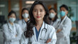 © D-stock photo - Portrait of young Asian female doctor standing in front of medical team