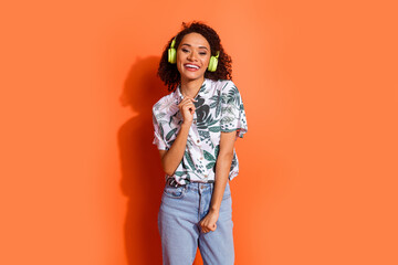 Poster - Photo portrait of brown wavy haired youngster girl wear shirt listen action playlist in wireless headphones isolated on orange color background