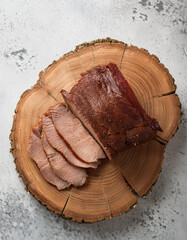 Wall Mural - Sliced smoked beef brisket on tree stump with cement floor. Fresh meat. Tasty and organic farm food