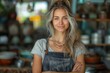 © DKPhoto - A woman with blonde hair in an apron, smiles warmly in a well-lit kitchen, with wooden shelves and culinary items blurred in the background.