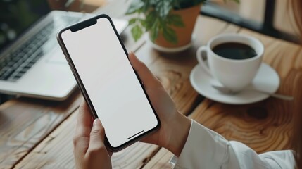 Mockup, using blank screen mobile phone with laptop and cup of coffee on table. finger touching on the cell phone screen, template for mobile app design or advertisement 