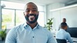 © LukaszDesign - Confident young mixed-race businessman smiling with hand on chin at his office with colleagues. Entrepreneur and leader dedicated to startup success with team