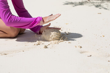 a girl plays with sand, a child builds a castle from sand