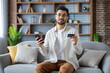 © Tetiana - Man using smartphone and holding credit card on couch at home
