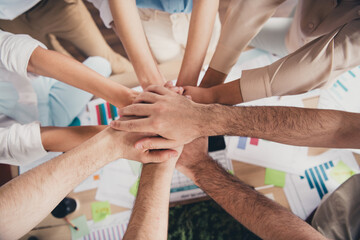 Poster - Above view cropped portrait of group professional corporate workers handshake pile stack arms business center indoors