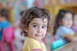 © Fotograf - A young girl sits at a table in a classroom, focused on her schoolwork