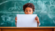 © Hanna - Young Boy Holding Blank White Paper in Front of Classroom Chalkboard