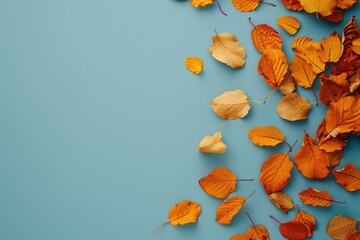 Poster - A collection of yellow and orange leaves scattered on a blue surface, perfect for autumn or nature-themed designs