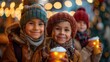 © Margo_Alexa - Children with beautiful glowing mugs of hot chocolate at the Christmas market, with holiday lights in the background.