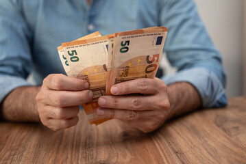 Poster - Businessman holds euro banknotes in hands counting money to pay for various utility bills as part of operating expenses for business sitting at workplace in office