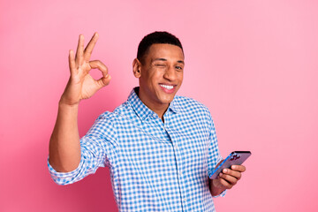 Sticker - Photo of cheerful positive guy dressed checkered shirt showing okey winking eye chatting device isolated pink color background