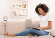 © Prostock-studio - African-american woman working on laptop computer, sitting on sofa at home, copy space