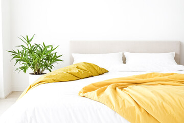 Poster - White bed with yellow blanket and green plant in the corner