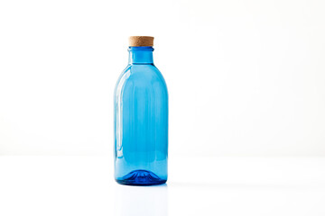 Poster - Blue Glass Bottle with Cork Top on White Background