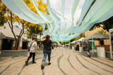 Zapopan, Jalisco, Mexico - June 7, 2024: Morning sun shines on people walking along the plaza of Arcos de Zapopan.