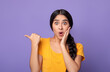 © Prostock-studio - Wow, Look Here. Amazed young indian woman pointing at copy space over purple studio background. Excited surprised lady indicating free space, showing place for advert or promotional text